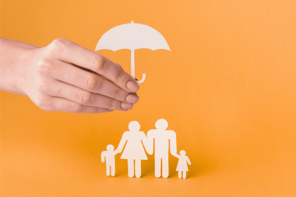 Close-up hand with paper cut umbrella protecting family