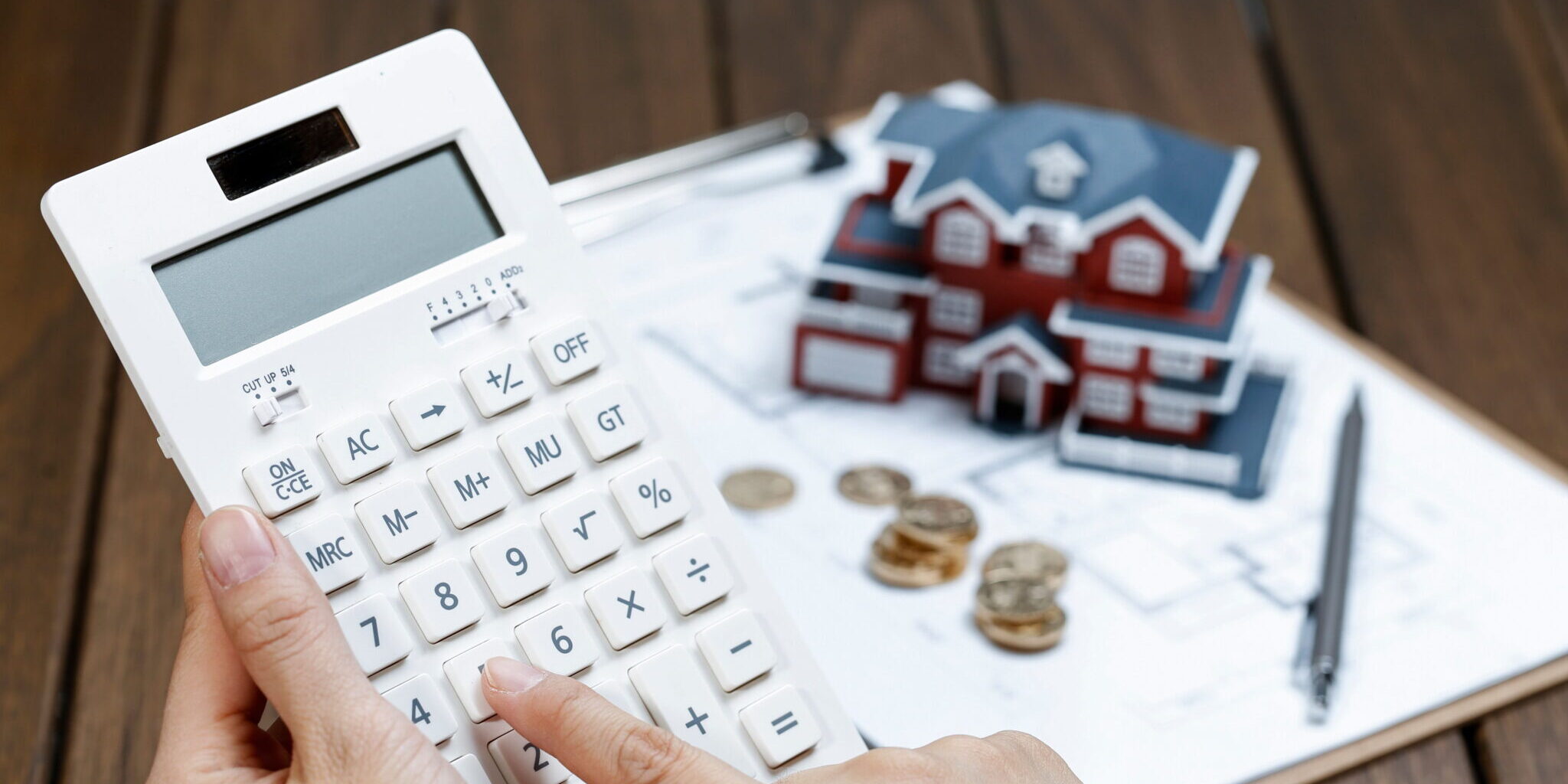 A female hand operating a calculator in front of a Villa house model